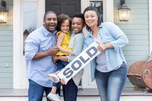 family outside new home holding sold sign