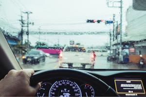 Driving in rainy day, Hand holding steering wheel with car traffic in the city in raining day
