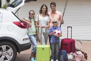 family outside house packed for vacation
