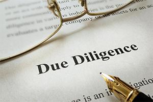 Due Diligence typed on a piece of paper with a fountain pen and glasses