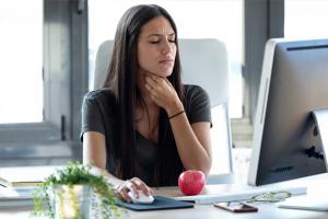 woman with sore throat at computer