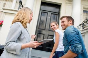 Real Estate Agent with a young couple at entrance of a condo/apartment