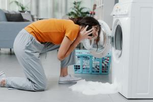 Woman inspecting leaky washing machine